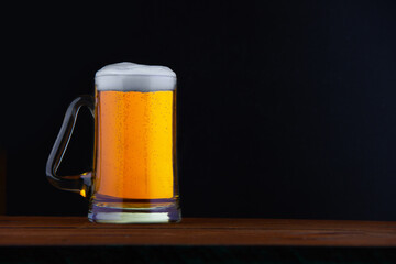 a mug of beer with foam on a black background and a place for the inscription