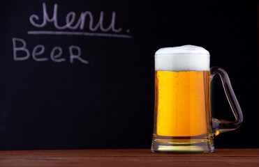 a mug of beer with foam on a black background and a place for the inscription
