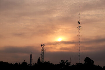 mosque minaret and communication tower during sunrise. radio frequency transmission tower