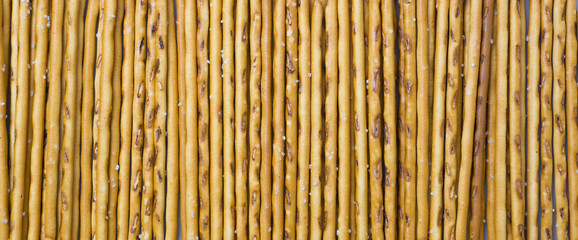 Background from sticks of crackers with salt. Food concept. Edible snacks dry sticks with salt. Texture from straws, crackers sticks.