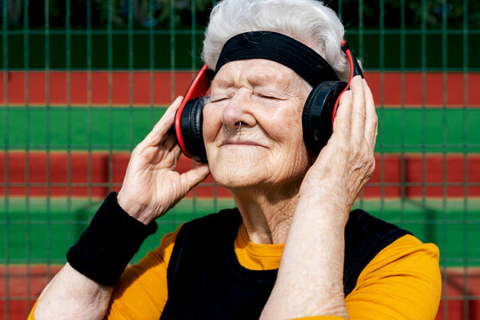 Senior woman in sportswear listening to music on court