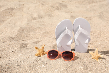 Stylish flip flops, sunglasses and starfishes on sand, space for text