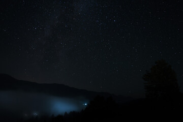 Beautiful view of misty mountains under starry sky at night