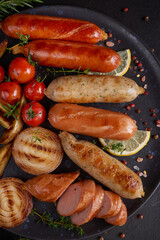 sausages and ingredients for cooking. Grilled sausage with the addition of herbs and and spices, vegetables, rosemary, thyme on the grill plate, Grilling food, bbq, barbecue, on stone table. Top view.