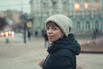 a girl in a winter hat walks around the city