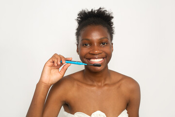 attractive young woman brushing teeth in towel on white background 