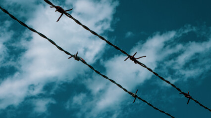 Barbed wire against a teal sky