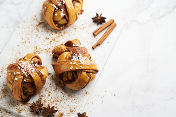 Fresh vegan cinnamon buns on marble board and white marble table