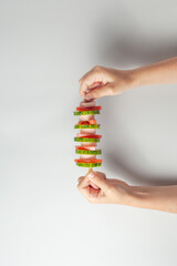 in the hands of a child an unusual sandwich on a sword. There's a sausage, a cucumber, a tomato.