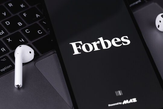 Forbes logo mobile app on screen smartphone iPhone with notebook keyboard background. Forbes is an American family-controlled business magazine. Moscow, Russia - July 22, 2021