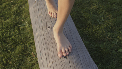 Kids bare feet walk on the wood log. Benefit of walking barefoot. Development of dexterity and coordination. 