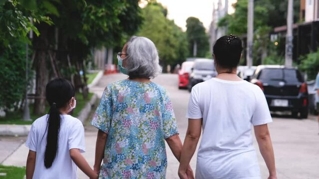 Asian girl  and woman holding grandmother's hand for a walk outside to relax