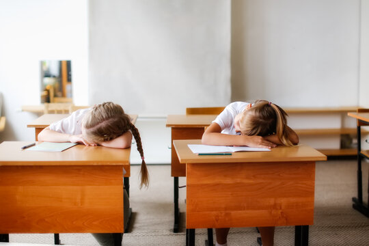 schoolchildren, children sleep at desks in bright classroom, the concept of school education and children's emotions, fatigue and overload at school. One minute of rest in classroom, relaxation