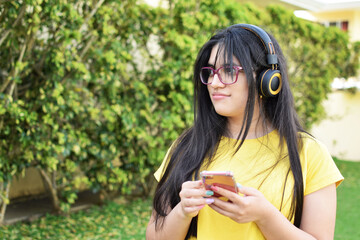 Mujer latina escuchando música con audífonos al aire libre. Mujer Guatemalteca joven con cabello...