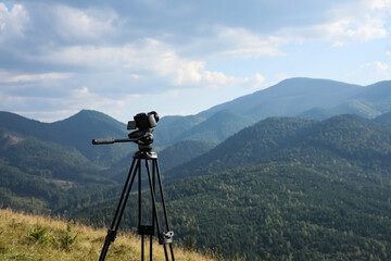 Tripod with modern camera in mountains on sunny day. Professional photography © New Africa