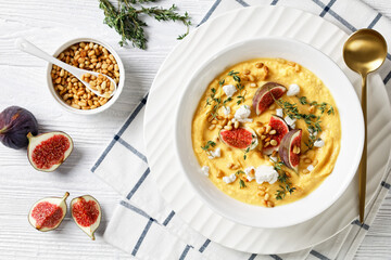 Pumpkin soup with feta, figs, pine nuts, top view