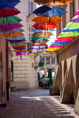 Fototapeta na wymiar Tarnow, Poland - July 24, 2021: Piekarska street near Town Square decorated with colorful umbrellas, modeled on the Portuguese 