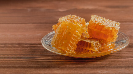 Honeycomb with bee honey on a glass plate. Wooden table. Copy space.