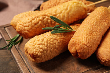 Delicious deep fried corn dogs on wooden board, closeup