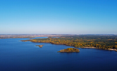 Obraz premium Island in the sea with a beautiful autumn forest. Aerial top view