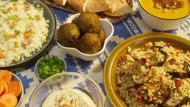 Arabian cuisine. Bulgur with eggplant, falafel, bean soup on table, couscous with chicken. Traditional middle eastern culture. Moutabal and vegetable salad in bowls, pita. Delicious rice with meat.