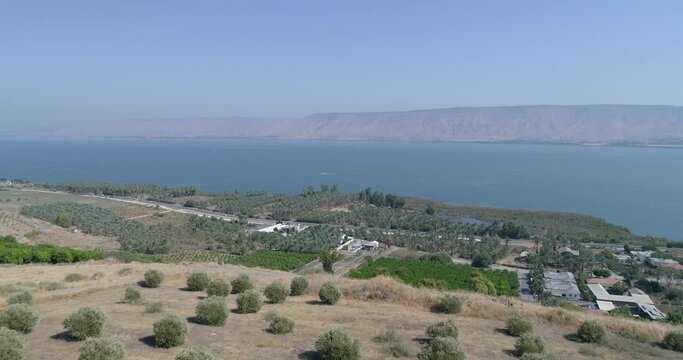 Aerial shot at sunset above Golan Heights and Tiberias with Galilee sea or Kinneret at Jordan valley in North of Israel. Drone above open fields with orange green landscapes and mountains with clear