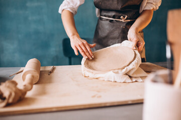 Young woman on a pottery class working with rolling pin