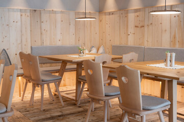 Newly paneled pine wood seating area with chairs and tables with pleasant, light ceiling lights