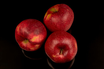 Three fresh red apples on black background