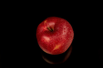 Fototapeta na wymiar Wet red apple on a black background. Water drops on a beautiful fresh apple.