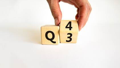 From 3rd to 4th quarter symbol. Businessman turns a wooden cube and changes words 'Q3' to 'Q4'....