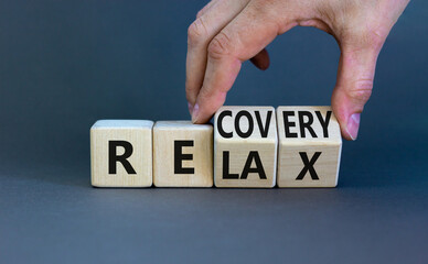 Relax and recovery symbol. Businessman turns cubes and changes the word 'relax' to 'recovery'. Beautiful grey table, grey background. Business, relax and recovery concept. Copy space.