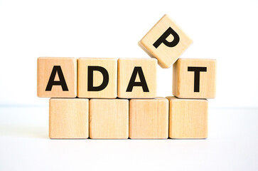 Adapt symbol. The concept word 'adapt' on wooden cubes. Beautiful white table, white background....