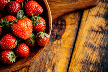 Fresh juicy strawberries with leaves on a wooden background