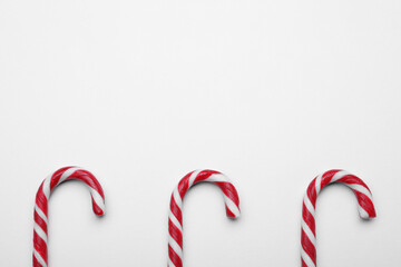 Many sweet Christmas candy canes on white background, flat lay. Space for text