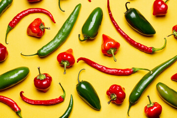 Hot peppers composition, pattern of peppers on yellow, top view.