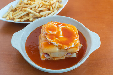 Francesinha is a Portuguese sandwich, made with bread, ham, linguica, sausage, steak, and covered with, cheese and beer sauce. Close up