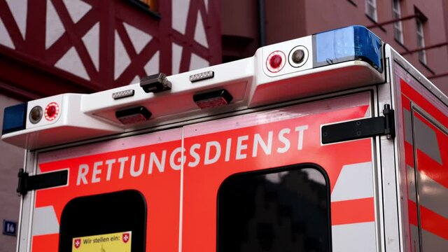 Frankfurt, Germany, October 2021: Red Malteser ambulance car with blue lights on in the city center, concept of emergency medical care, patient transportation in van to hospital
