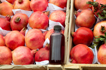 freshly squeezed pomegranate juice in a plastic bottle on boxes with pomegranates