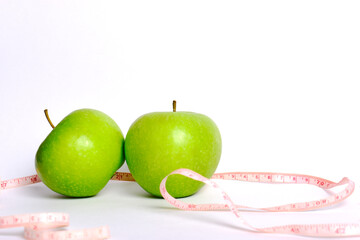 A perfect fresh green apple with a centimeter for measuring the body, isolated on a white background