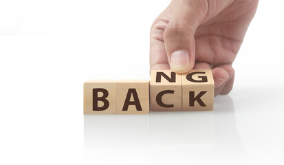 The hand puts  wooden cube with the letter  from the word back and bang. wooden cubes standing  in hand