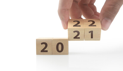 The hand puts  wooden cube with the letter  from the 2022 2021. wooden cubes standing  in hand