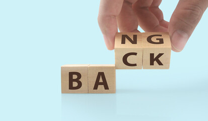 The hand puts  wooden cube with the letter  from the word back and bang. wooden cubes standing  in hand