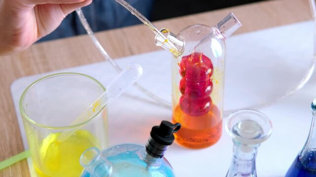two children 7-9 years old, elementary school boys, do chemical experiments, pour colored liquids into glass flasks, mix colors, school education concept, hands-on study of chemistry