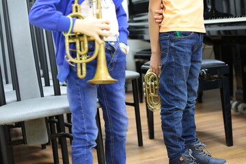 Two children young musicians with a musical trumpet standing in the classroom at the lesson...