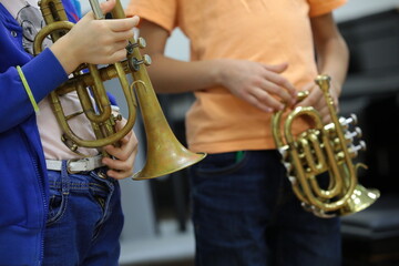 Kids young musicians standing with a musical instrument trumpet in hand frontal view close-up - obrazy, fototapety, plakaty