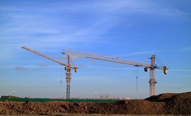 An image of a tower crane against the background of a house under construction.