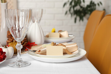 Beautiful autumn place setting with blank card and decor on table indoors