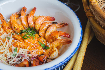 Traditional bright shrimp risotto in a bowl on a table in a restaurant with a beautiful decor in a dark key close-up.