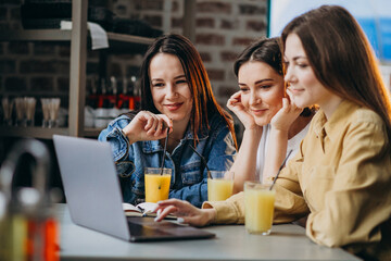 Three girls students preparing for exam with laptop in a cafe